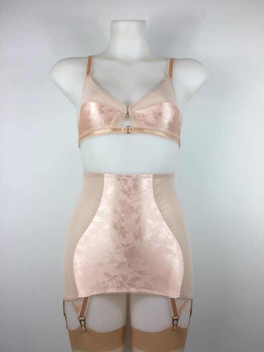 faux vintage inspired longline girdle and front fastening bralette in peachy floral satin fabric. Longline girdle has 6 beige suspender clips holding up seamed nylon stockings. Matching garter belt, longline underwired bra and pantie girdle 