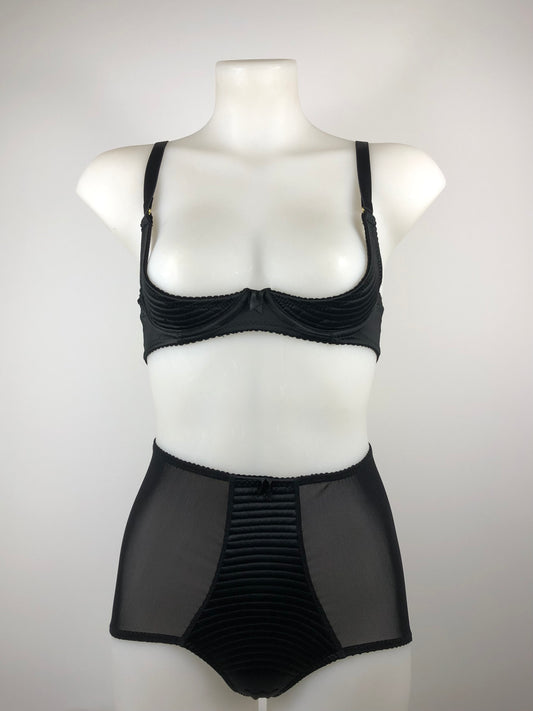 A black satin quarter cup underwired bra with spiral stitching and gold hardware, displayed on a mannequin.