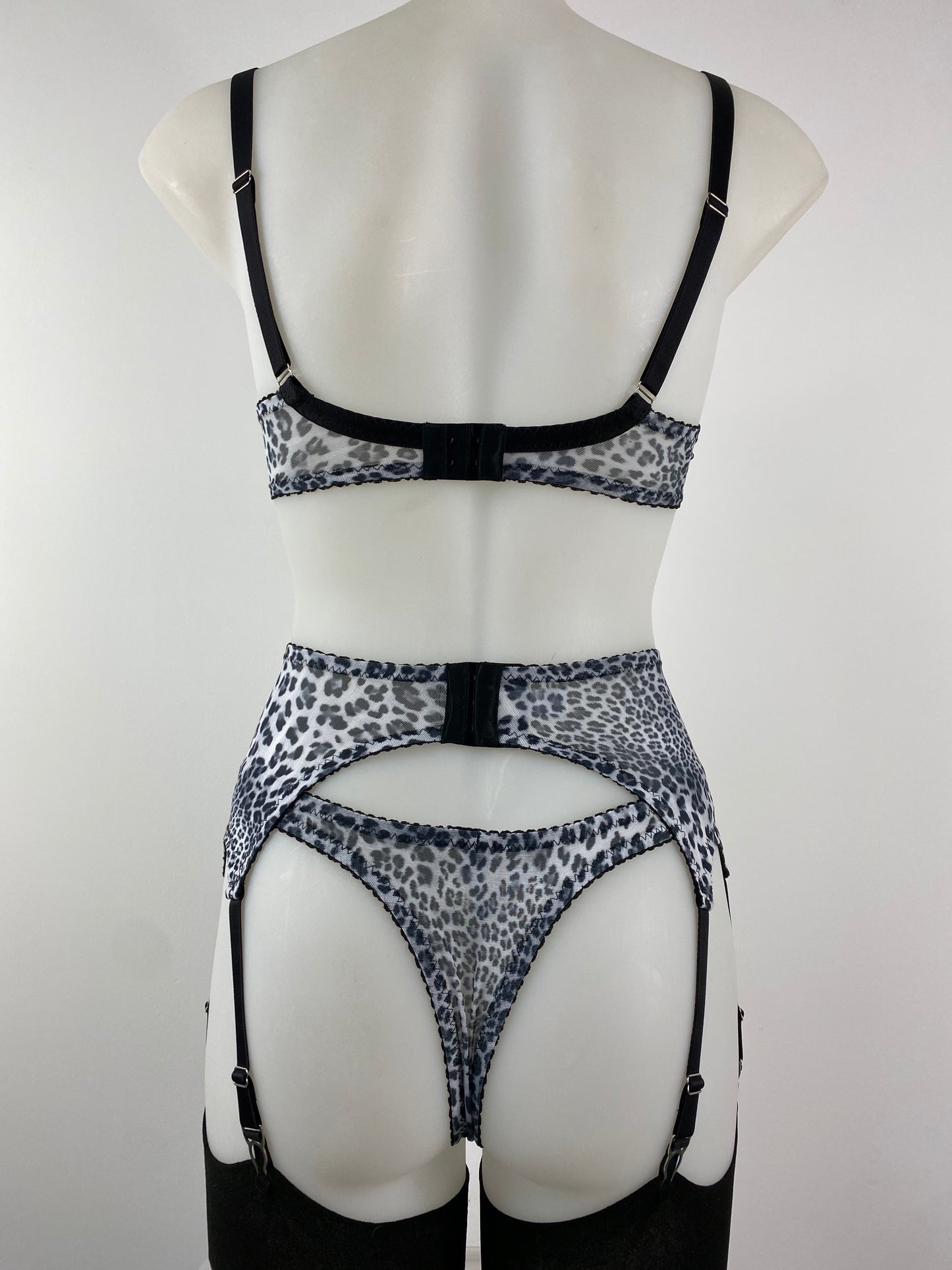Pip & Pantalaimon Monochrome Suspender Belt with black satin front, leopard mesh sides, and six sturdy steel suspender clips attached to stockings, worn at the waist.