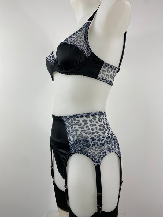 The Pip & Pantalaimon Monochrome Underwired Bra with black satin lower cups, sheer leopard mesh top cups, vintage-style projection, and dual fastening, shown from the front.