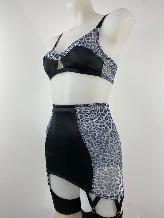 The Pip & Pantalaimon Sleek Longline Girdle in black satin with monochrome leopard mesh side panels, six steel suspender straps, and back hook fastening, styled with stockings.