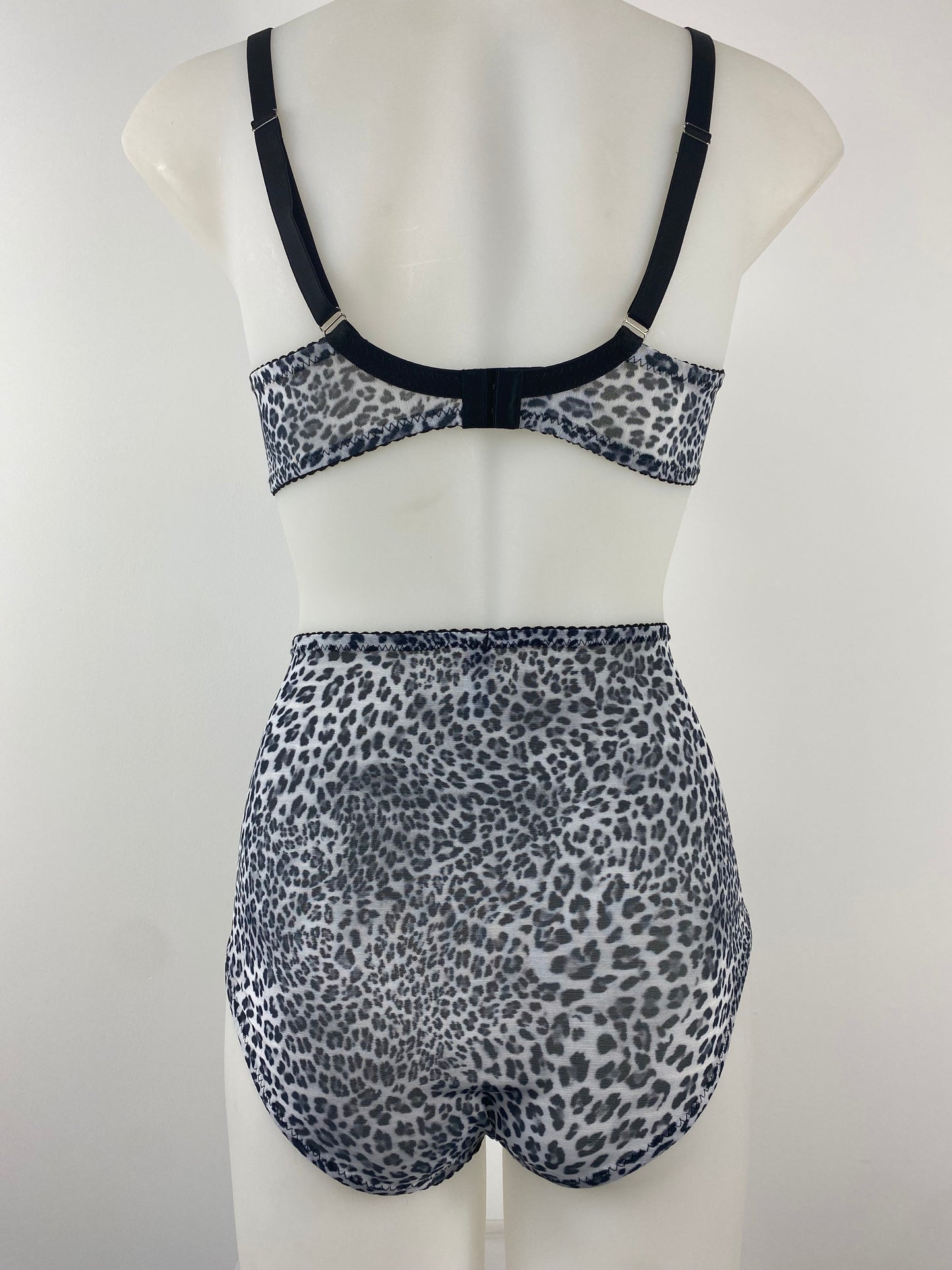 Front view of the Pip & Pantalaimon Monochrome Bralette with black satin lower cups and leopard mesh top cups and wings, featuring a vintage shape and front hook closure.