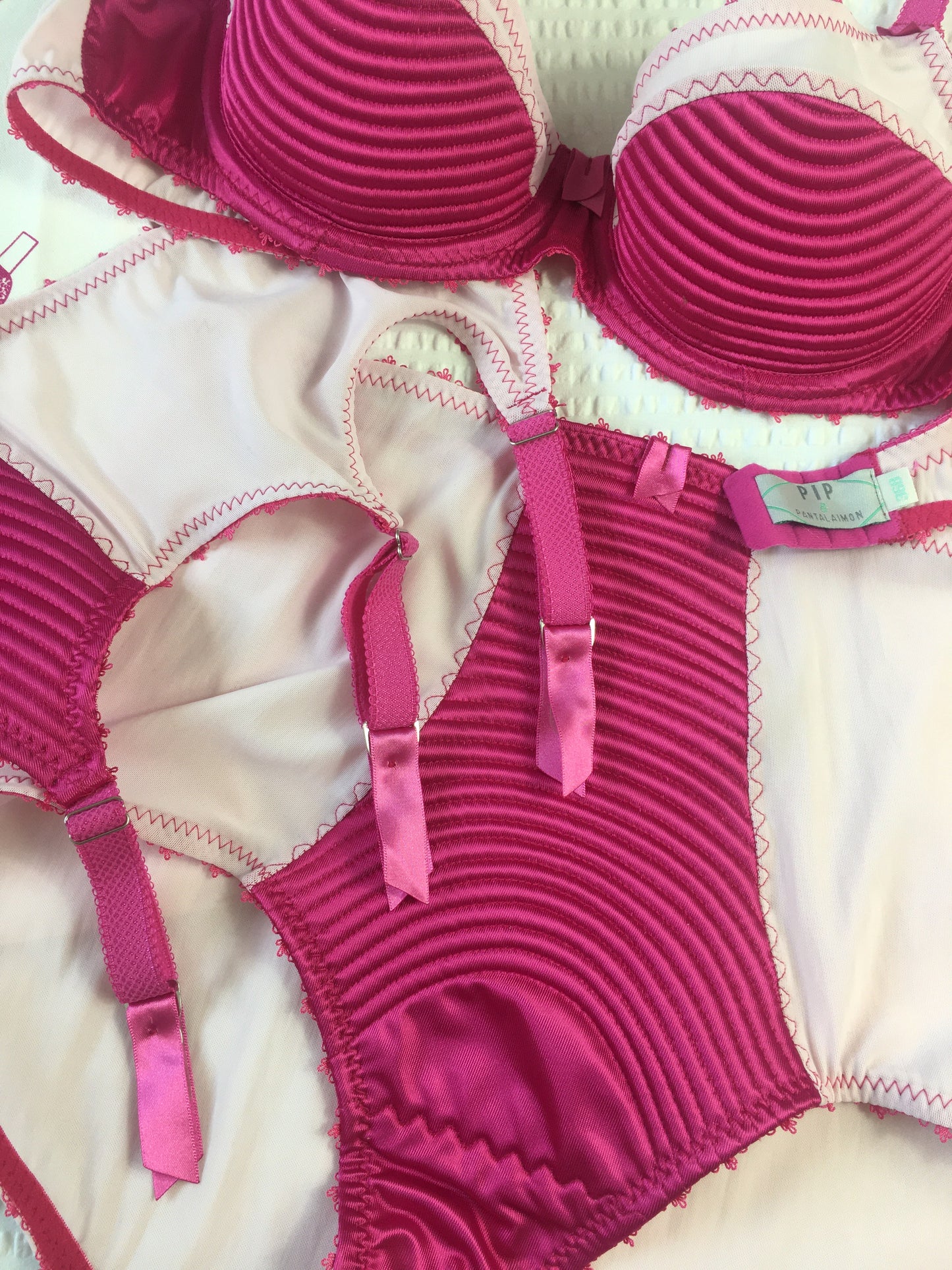hot pink padded underwired bra with pale pink mesh and vintage style spiral stitching on the lower cup. Inspired by vintage 1950s bullet bras but with a softer modern shape. Matching 6 strap suspender belt with metal garter clips and high waisted pantie girdle knicker also available. Barbie vibe lingerie and underwear to be worn with seamed stockings