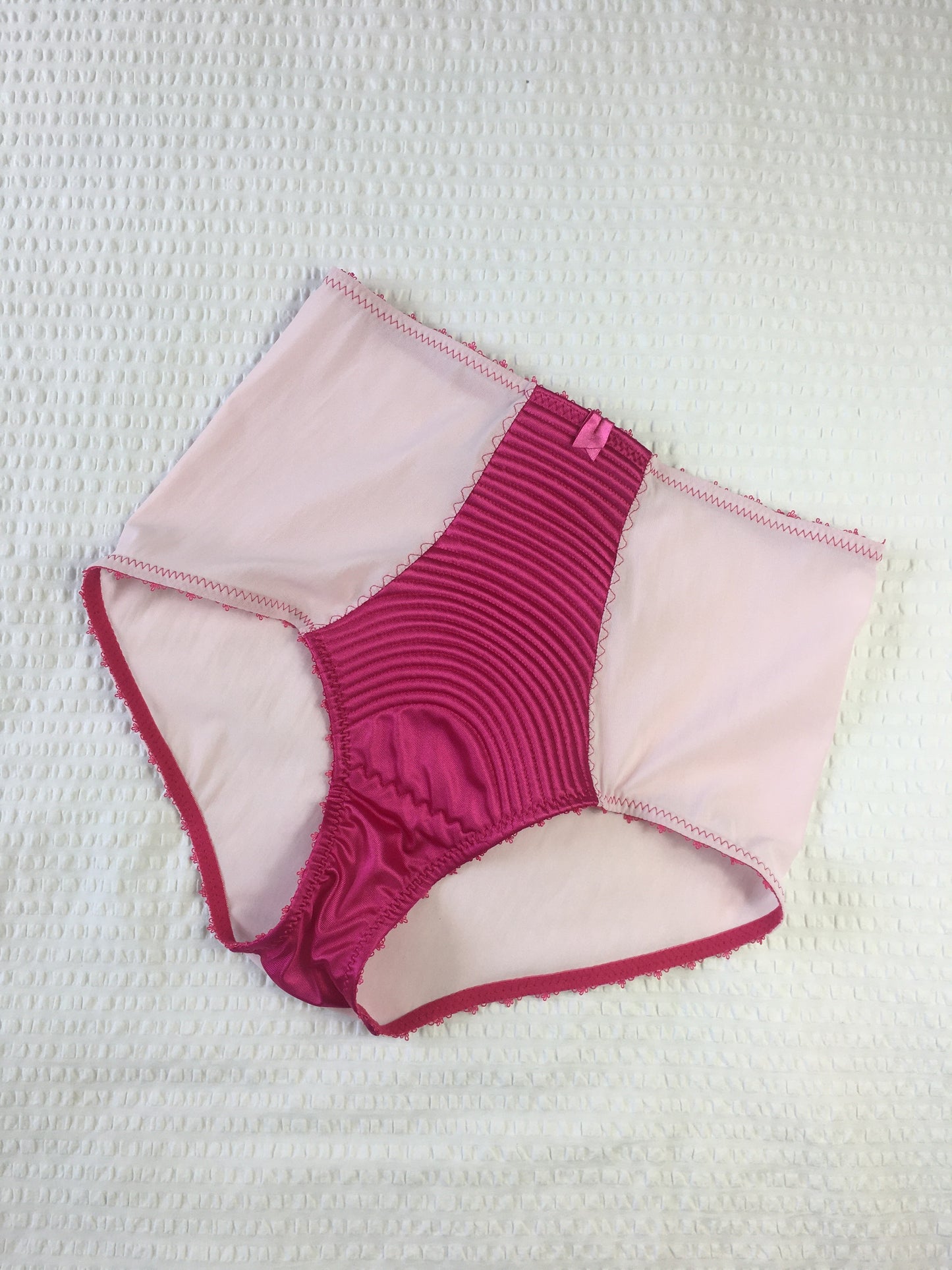 hot pink padded underwired bra with pale pink mesh and vintage style spiral stitching on the lower cup. Inspired by vintage 1950s bullet bras but with a softer modern shape. Matching 6 strap suspender belt with metal garter clips and high waisted pantie girdle knicker also available. Barbie vibe lingerie and underwear to be worn with seamed stockings