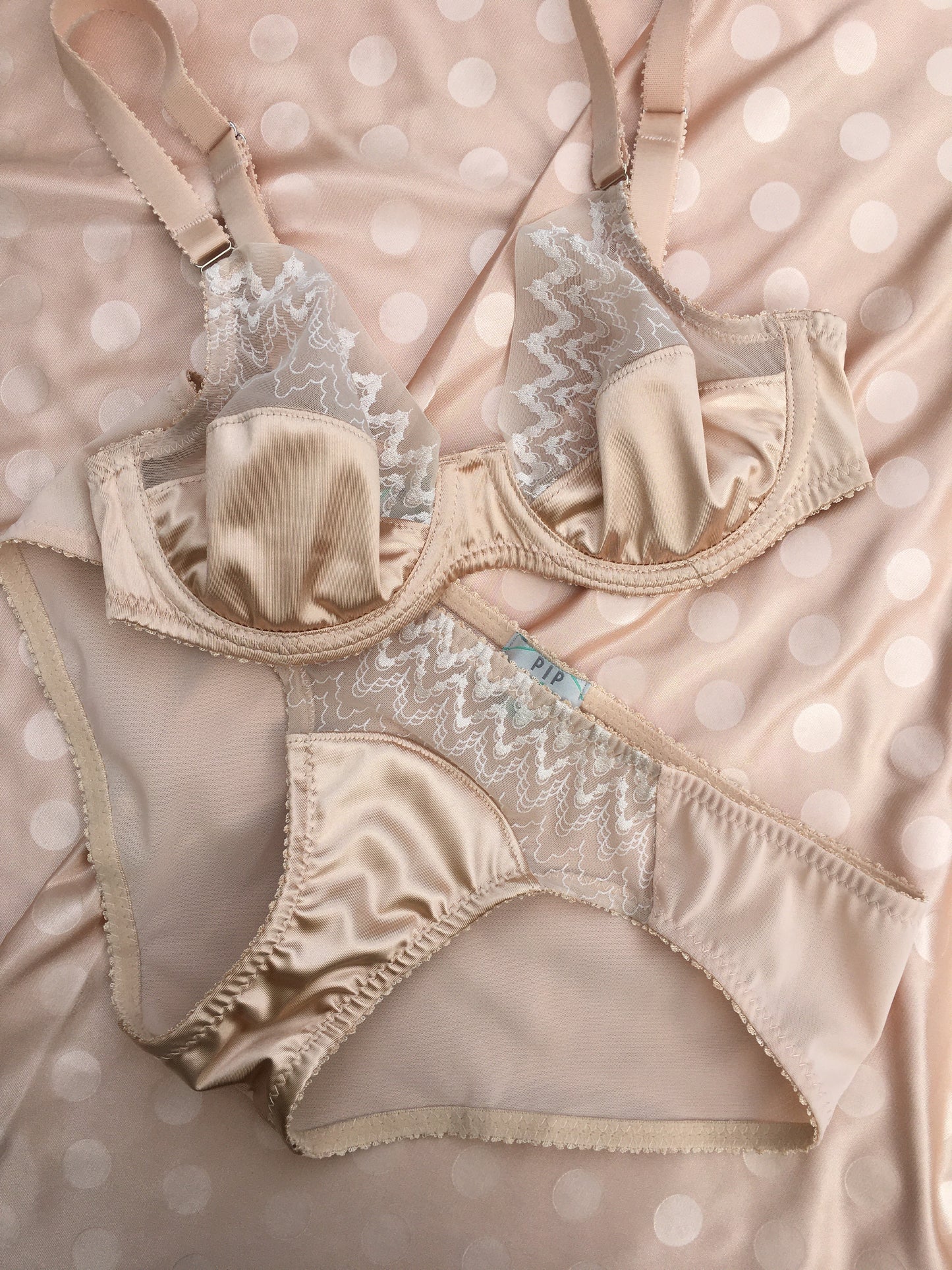 1920s inspired lingerie with art deco style sheer tulle embroidery. 1930s vintage style underwear, perfect for great Gatsby themes events. Art deco underwired bra with sheer retro art deco lace, six strap suspender belt and classic cut pantie knicker. Steel garter clips. Burlesque sheer nude skin peach biscotti lingerie and underwear made in the UK.