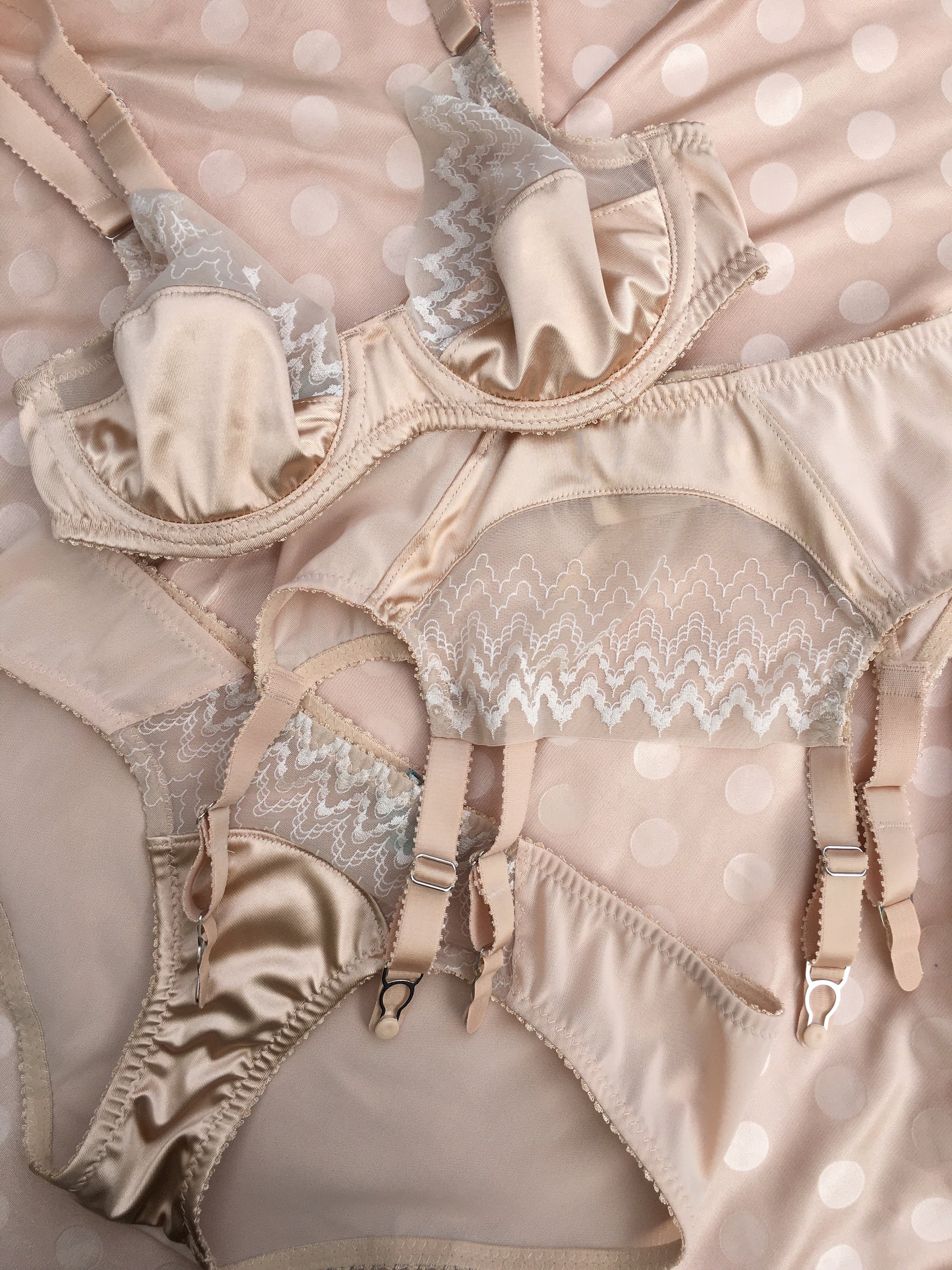 1920s inspired lingerie with art deco style sheer tulle embroidery. 1930s vintage style underwear, perfect for great Gatsby themes events. Art deco underwired bra with sheer retro art deco lace, six strap suspender belt and classic cut pantie knicker. Steel garter clips. Burlesque sheer nude skin peach biscotti lingerie and underwear made in the UK.