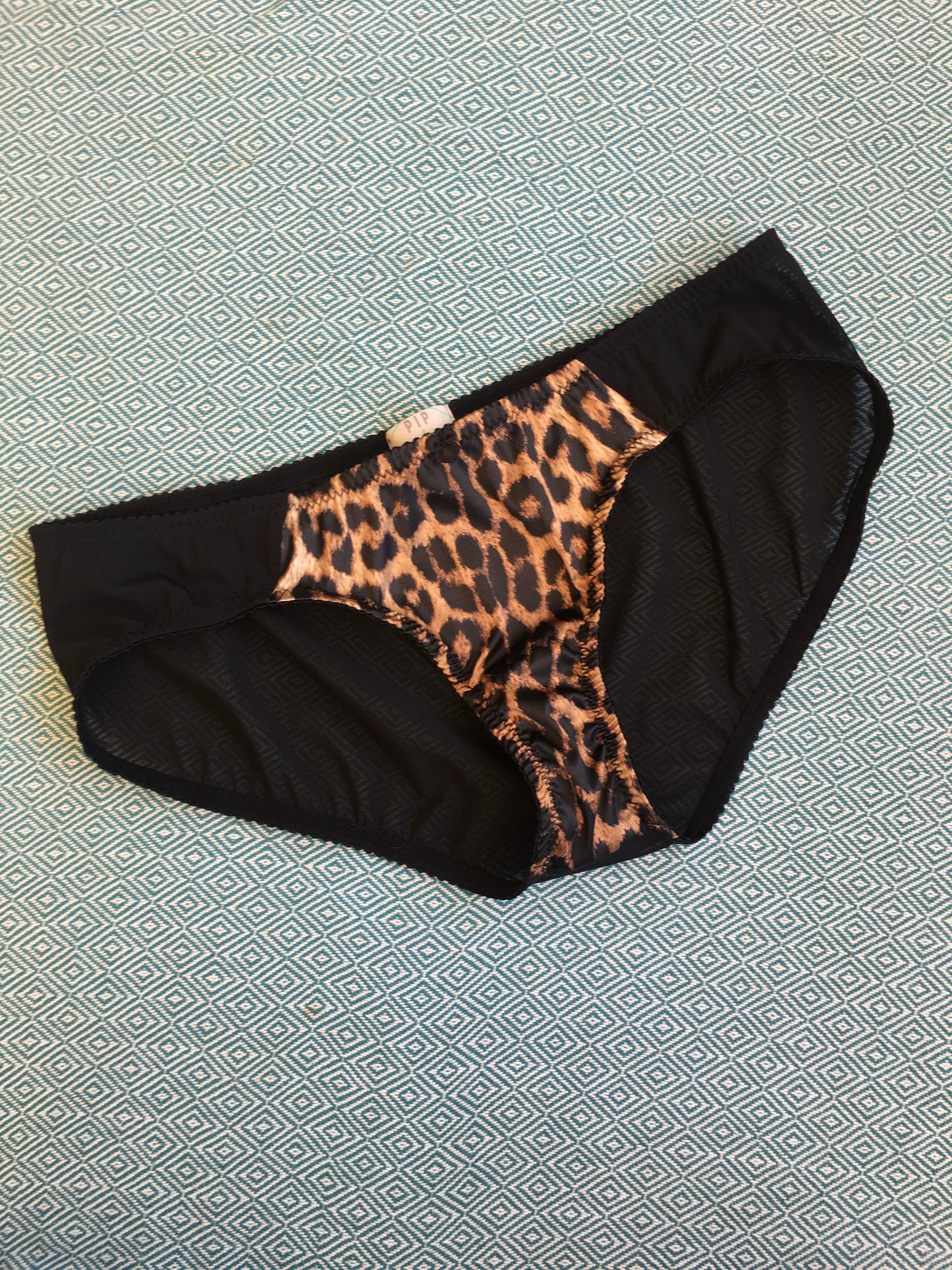 vintage inspired lingerie garter belt six stray suspender belt with Y straps in leopard print. Vintage inspired fetish bettie page bullet bra lingerie by pip and pantalaimon. Retro underwear made in the UK in animal print. Soft bra, front fastening bralette and classic cut panties knickers. 3 piece lingerie set paired perfectly with seamed stockings
