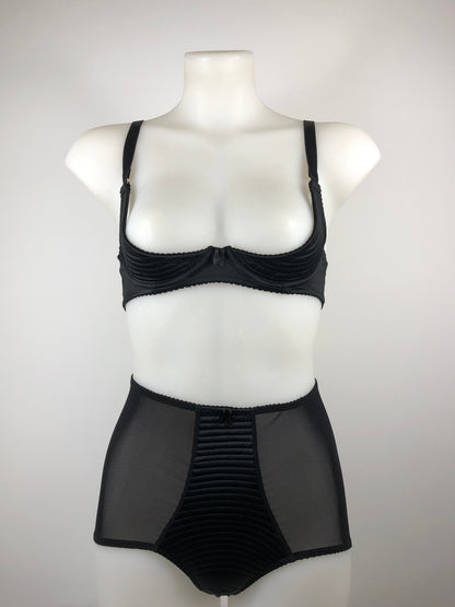 A black satin quarter cup underwired bra with spiral stitching and gold hardware, displayed on a mannequin.
