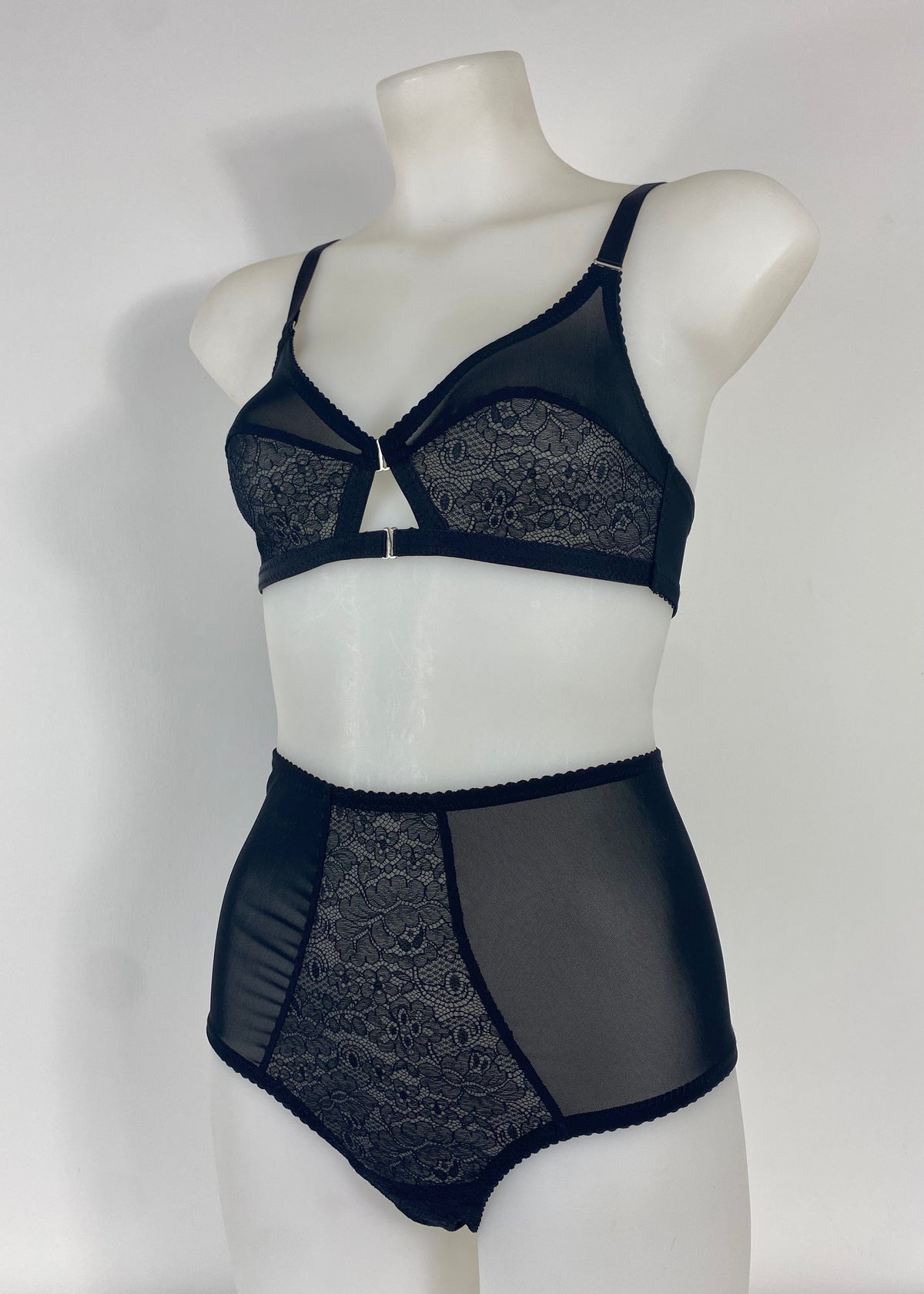 Black lace and sheer mesh lingerie set displayed on a white mannequin torso, featuring a bralette and high-waisted briefs against a plain light background.