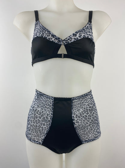 Front view of the Pip & Pantalaimon Monochrome Bralette with black satin lower cups and leopard mesh top cups and wings, featuring a vintage shape and front hook closure.