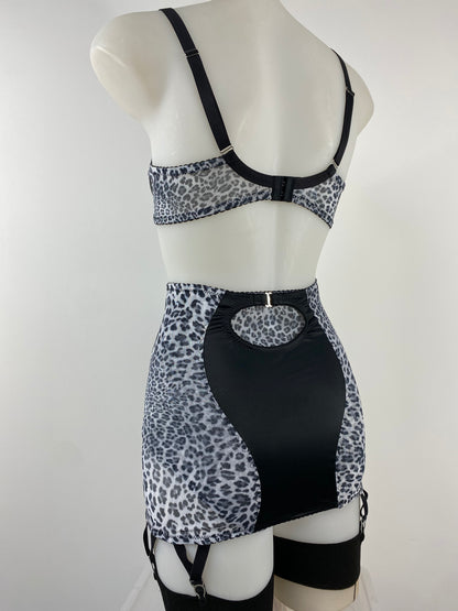 The Pip & Pantalaimon Sleek Longline Girdle in black satin with monochrome leopard mesh side panels, six steel suspender straps, and back hook fastening, styled with stockings.