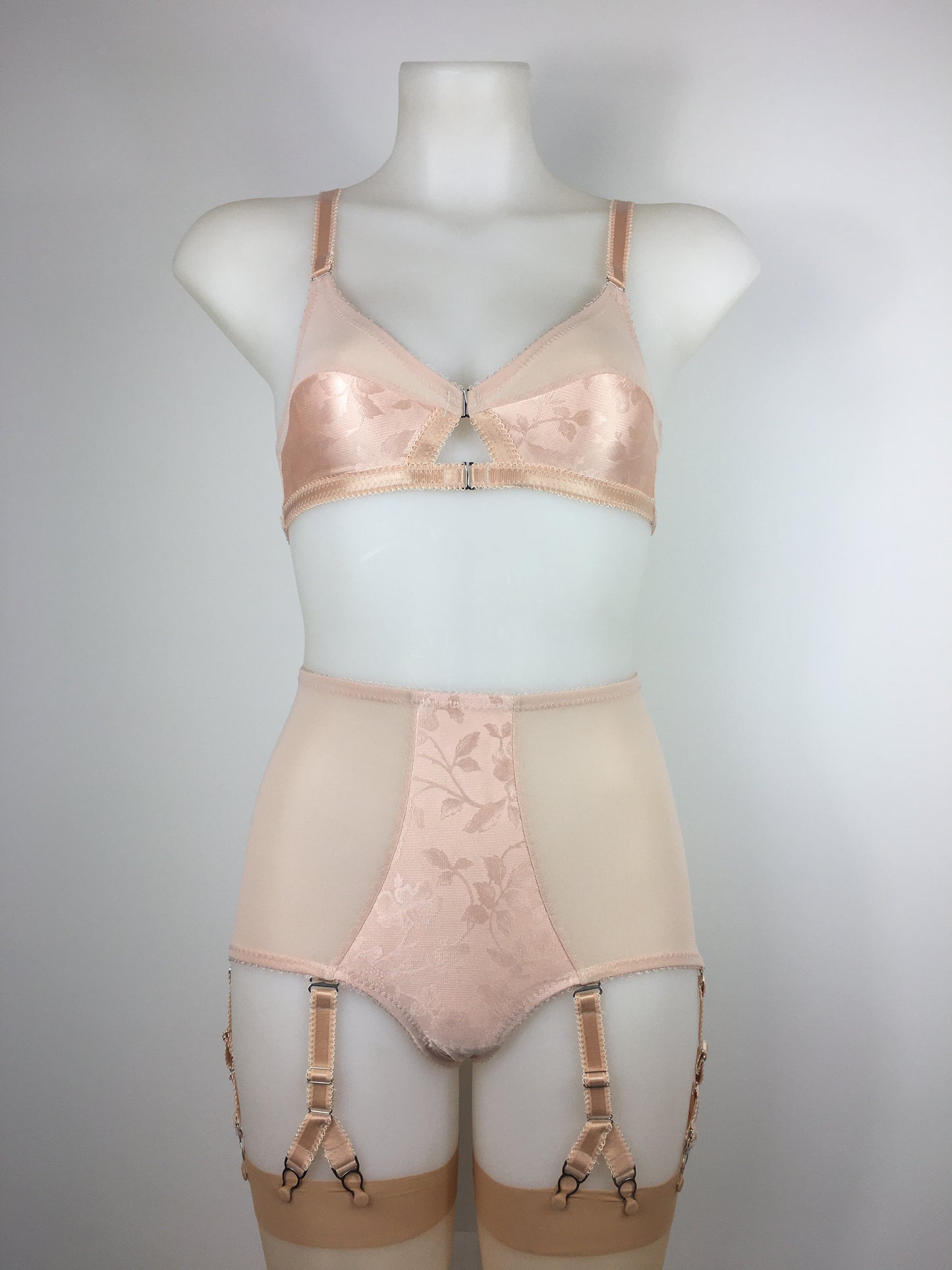 Our most authentic looking vintage inspired lingerie yet. Perfect peachy satin front fastening soft bra with faux vintage peach lower cups and nude biscotti mesh upper cups. Fastens at the front with two hooks. Our signature bralette shape makes the perfect faux 1950s 1940s bra. Not as pointed as a bullet bra, the bra gives a subtle vintage silhouette