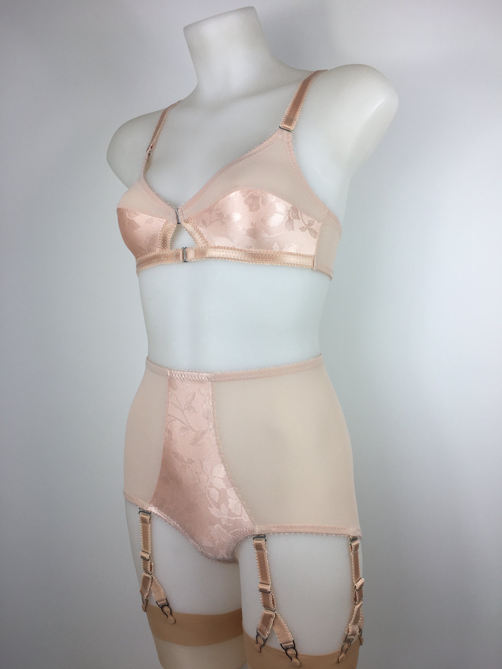 Our most authentic looking vintage inspired lingerie yet. Perfect peachy satin front fastening soft bra with faux vintage peach lower cups and nude biscotti mesh upper cups. Fastens at the front with two hooks. Our signature bralette shape makes the perfect faux 1950s 1940s bra. Not as pointed as a bullet bra, the bra gives a subtle vintage silhouette