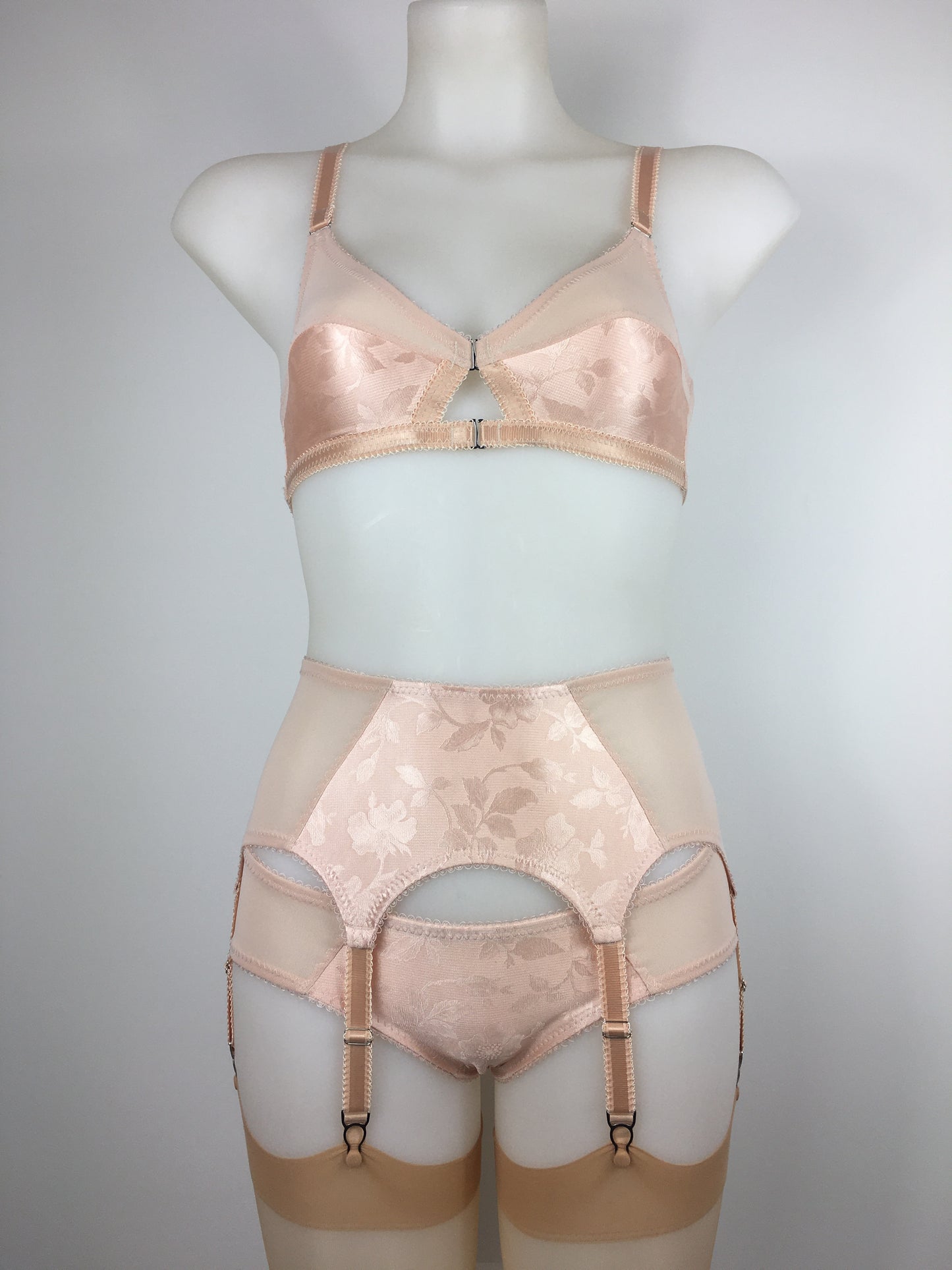 Our most authentic looking vintage inspired lingerie yet. Perfect peachy satin front fastening soft bra with faux vintage peach lower cups and nude biscotti mesh upper cups. Fastens at the front with two hooks. Our signature bralette shape makes the perfect faux 1950s 1940s bra. Not as pointed as a bullet bra, the bra gives a subtle vintage silhouette