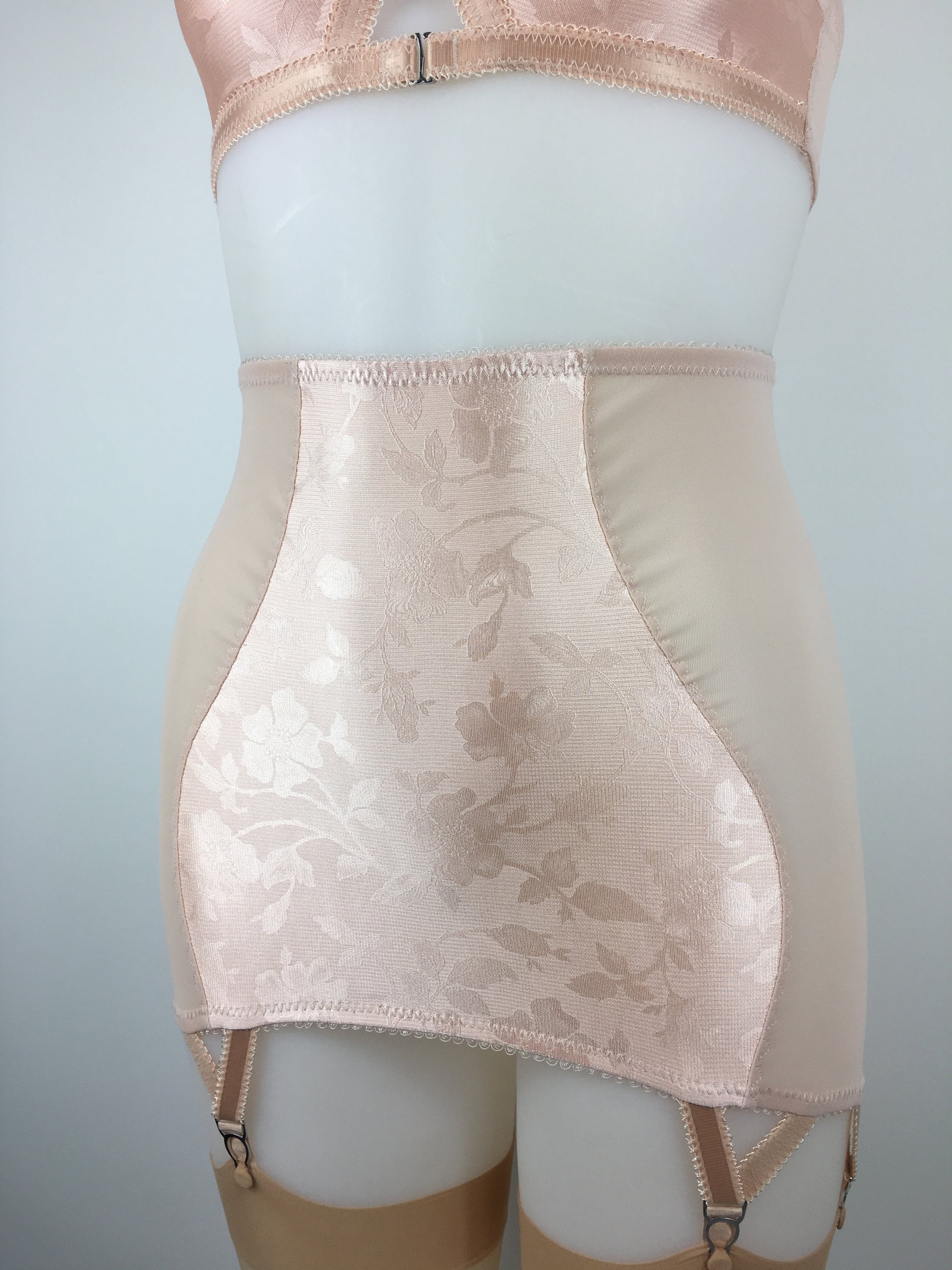 Our most authentic looking vintage inspired lingerie yet. Perfect peachy satin longline girdle with satin front and back panels. Keyhole back fastens with a steel hook after you've wiggled in. Perfect teamed with our faux vintage 1950s longline bra. The longline girdle has 6 metal suspender garter straps to keep your seamed stockings in place. Reproduction nude vintage lingerie made in the uk