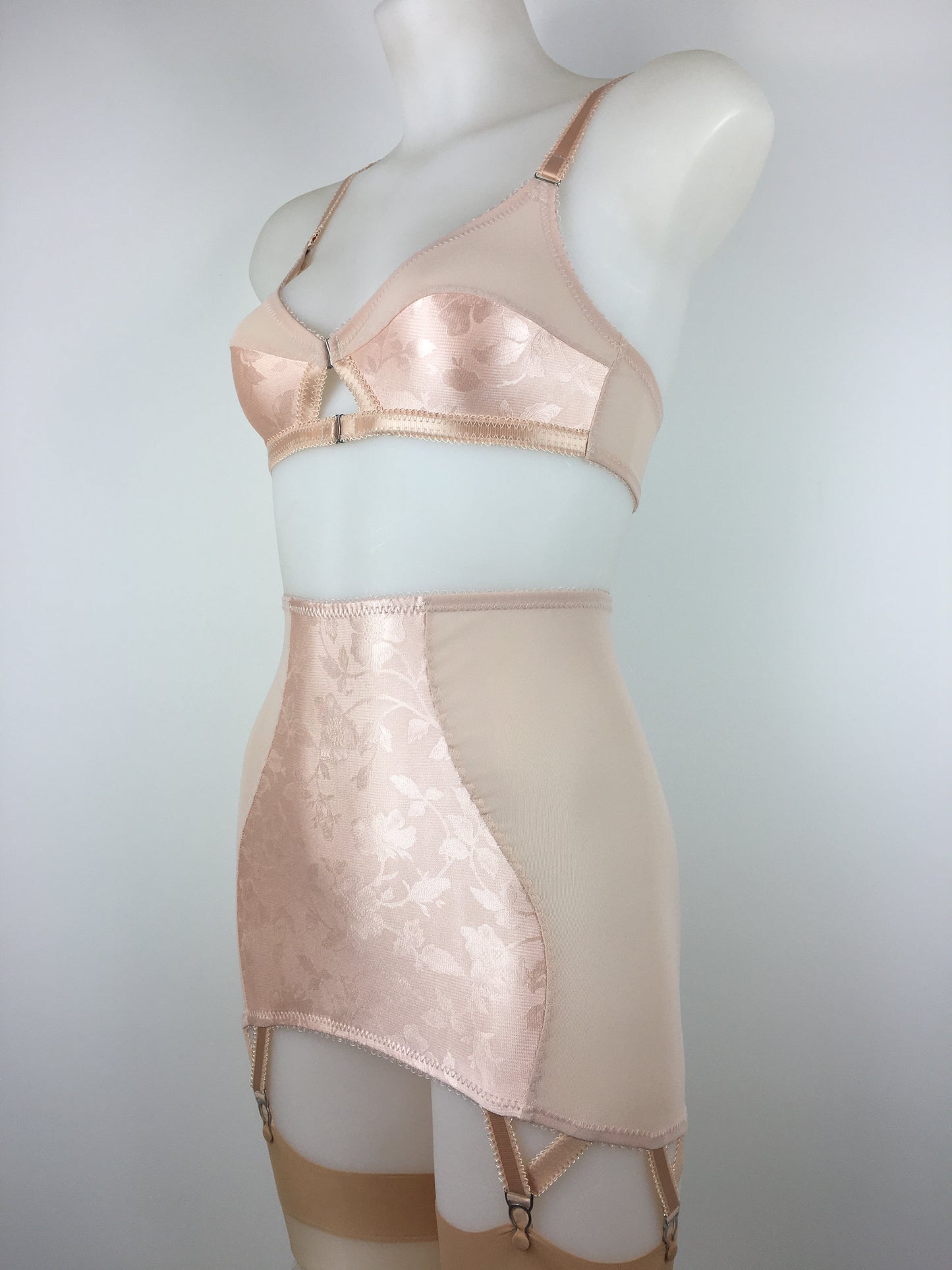 Our most authentic looking vintage inspired lingerie yet. Perfect peachy satin front fastening soft bra with faux vintage peach lower cups and nude biscotti mesh upper cups. Fastens at the front with two hooks. Our signature bralette shape makes the perfect faux 1950s 1940s bra. Not as pointed as a bullet bra, the bra gives a subtle vintage silhouette