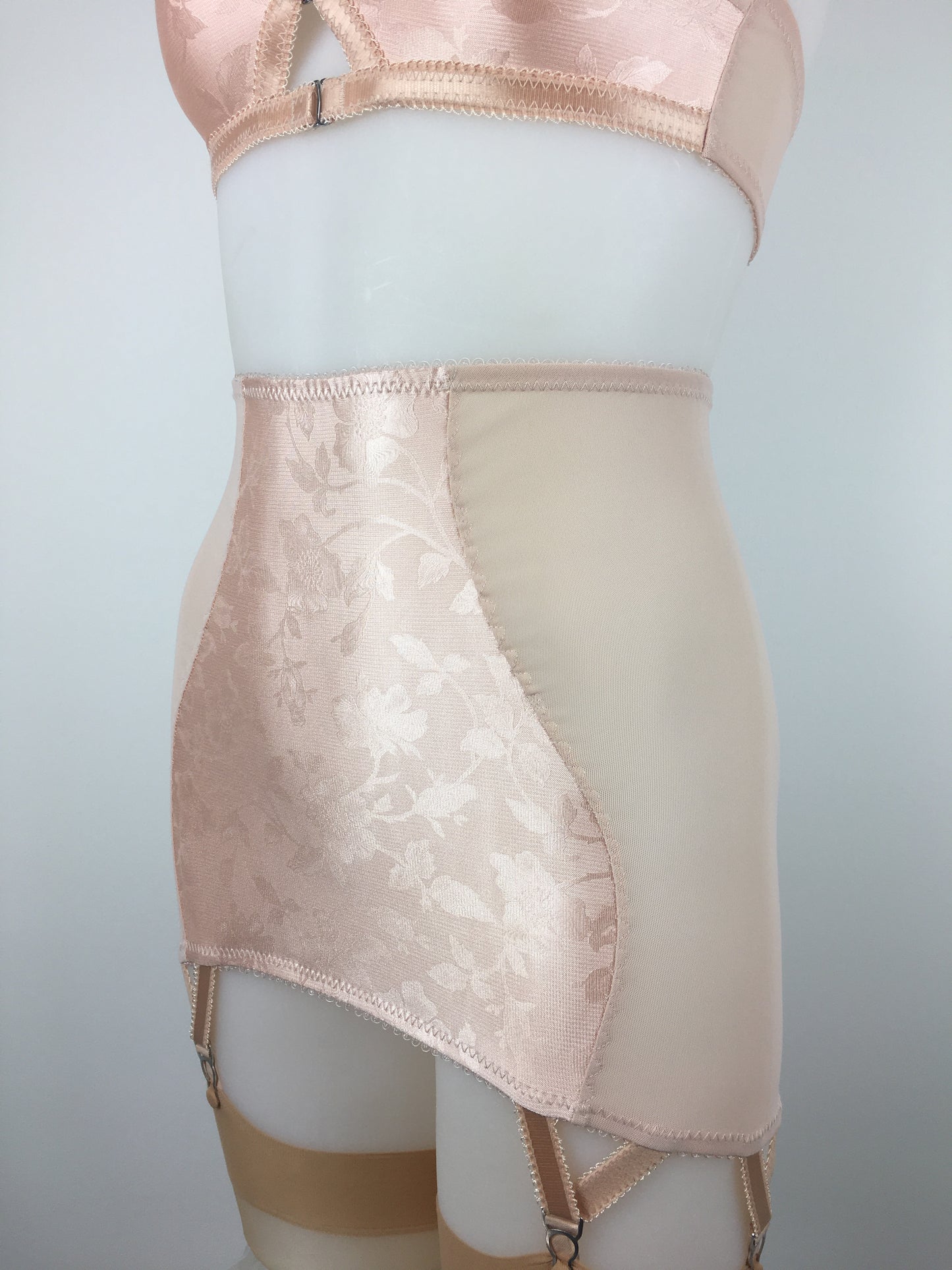 Our most authentic looking vintage inspired lingerie yet. Perfect peachy satin longline girdle with satin front and back panels. Keyhole back fastens with a steel hook after you've wiggled in. Perfect teamed with our faux vintage 1950s longline bra. The longline girdle has 6 metal suspender garter straps to keep your seamed stockings in place. Reproduction nude vintage lingerie made in the uk