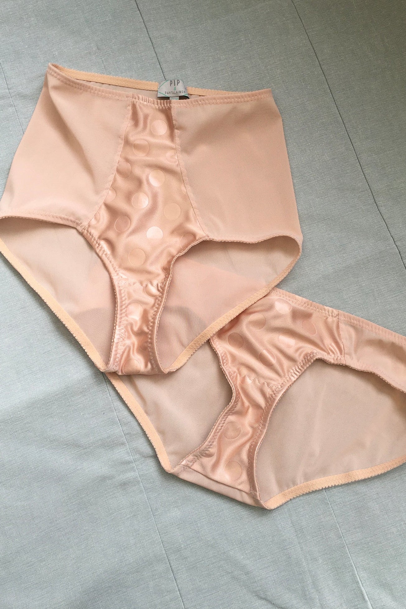 Vintage 1950s inspired shapewear lingerie underwear girdle girdlette longline 1940s suspender belt garter belt in muted vintage peach biscotti colour. Embodded large polka dot Goodwood pattern. Nude 1940s lingerie with six steel suspender clips for nylon seamed stockings, soft bra front fastening bralette and classic cut kickers or high waisted pantie girdles. Fetish bettie page style lingerie made in the UK by Pip and Pantalaimon